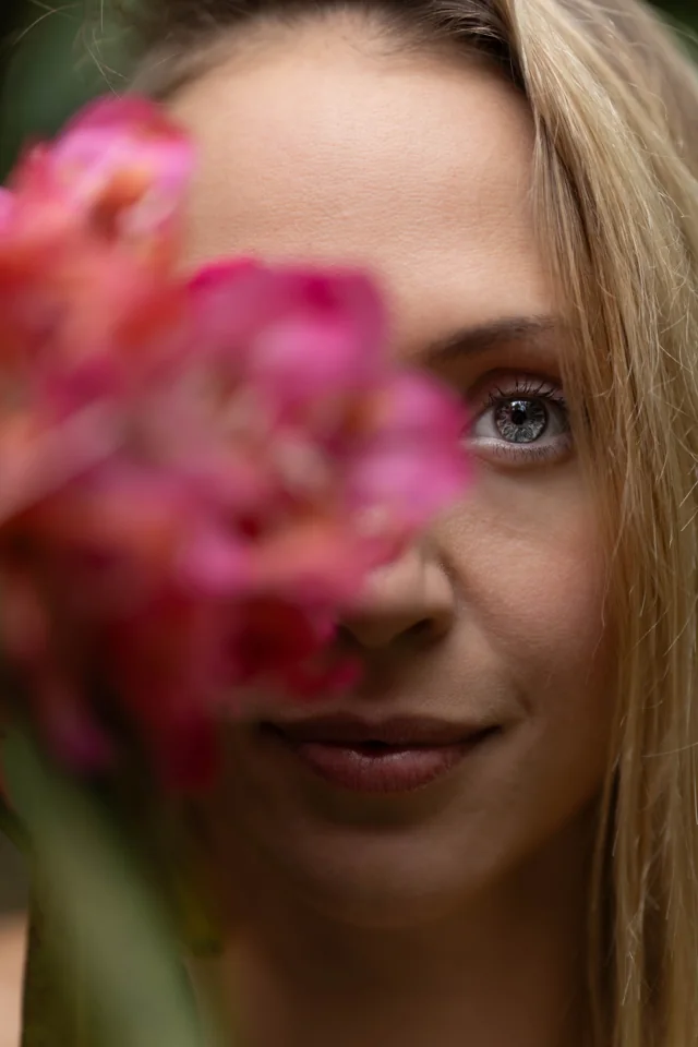 Close portrait of a woman with pink flowers partly covering her face