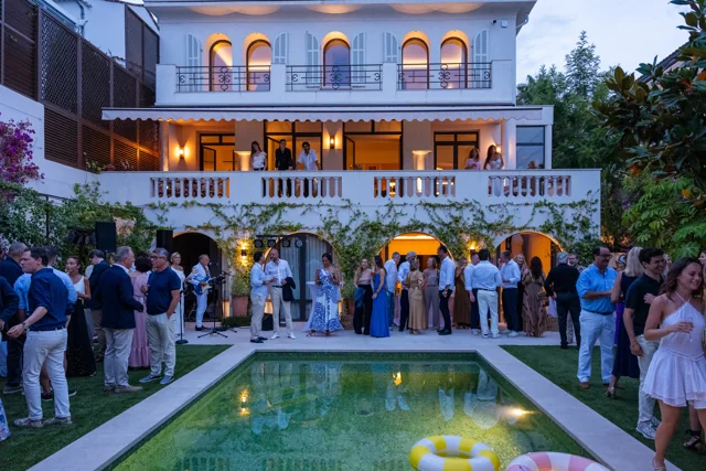 Guests gathered around a pool during an evening reception at a villa in Cannes